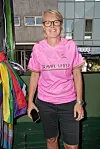 Person i pink Travel Sense-trøje med regnbuedetaljer står på en vogn med regnbueflag i byrum.