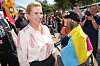 Smilende person taler med deltager iført flerfarvet pride-flag ved udendørs parade