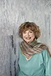 Smilende ældre kvinde ved lys marmoreret væg