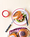 Åben burger med grønt og tomat på tallerken ved siden af dip og ekstra boller.