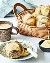 Tallerken med rundstykker, smørkniv, kaffe og kurv med brød på morgenbord