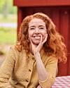 Johanne Louise Schmidt ved rødt træhus og ternet bord