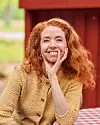 Johanne Louise Schmidt ved rødt træhus og ternet bord