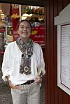 Smilende deltager fra Hotel romantik står foran bod på Bakken med glas vin.