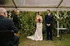 Brudepar står foran ceremonileder ved udendørs havebryllup.