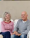 Ældre par sidder ved siden af hinanden i sofaen i en lys stue
