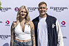 To personer står og smiler foran Temptation Island premierevæg med TV3 og Viaplay logoer.