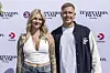 To personer står og smiler foran Temptation Island premierevæg med TV3 og Viaplay logoer.