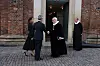 Præst i sort kjole giver hånd til gæst foran kirkeindgang
