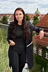 Person står på tagterrasse med udsigt over røde tage i København
