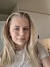 Portrett av en kvinne foran lyse kjøkkenskap innendørs.