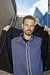 Svend Brinkmann på stentrappe udendørs, der holder sin sorte jakke åben over en blå skjorte.