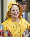 Dronning Margrethe i gul regnfrakke og hat under udendørs fejring i Arendal