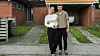 Julie og Oscar står foran deres gule hus med carport i et villakvarter.