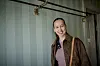 Merete Mærkedahl står smilende foran lyse, stribede vægge på Badehotellet i Oplevelsescenter Nyvang.