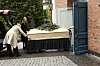 Lys kiste med blomster køres på vogn ind gennem en åben kirkedør