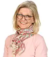 Smilende kvinne med briller, blondt hår og fargerikt skjerf mot hvit bakgrunn.