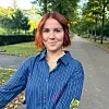 Kvinde med rødt hår på stille vej omgivet af træer og efterårsløv