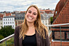 Alexandra Mosholt Søgaard på tagterrasse med røde tegltage i baggrunden