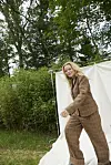 Kvinde i brun habit går foran lys fotobaggrund i grøn skov
