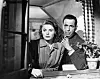 Ingrid Bergman og Humphrey Bogart står tæt ved et åbent vindue i en sort-hvid filmscene.