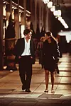 Julia Roberts og Hugh Grant går sammen på et oplyst fortov om aftenen i en scene fra 'Notting Hill'.