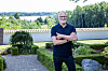 Lars Bom står i Aagerup Kirkes have med grønt anlæg og udsigt til søen bagved.