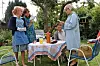 Skuespillere fra Krøniken står og sidder ved et lille havebord i en grøn villahave.