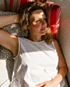 Kvinde ligger på puder i en sofa med sollys i ansigtet
