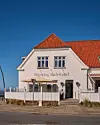 Hjerting Badehotels hvide facade med rødt tag og indgang ud mod vejen.