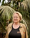 Kvinde i zoologisk have-uniform foran tætte palmeblade
