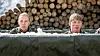 To personer i militærtøj sidder i et isfyldt udendørs bassin foran en brændestabel.