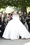 Model i stor hvid brudekjole går på udendørs catwalk foran siddende publikum