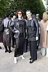 To kvinder i sorte outfits og læderjakker står blandt gæster ved udendørs Strax‑arrangement