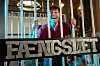Morten Münster står smilende bag tremmer med et stort skilt med teksten Fængslet