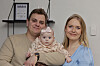 Maria og Nikolaj fra “Årgang 20” sidder hjemme med deres baby foran en lys væg.