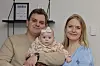 Maria og Nikolaj fra “Årgang 20” sidder hjemme med deres baby foran en lys væg.
