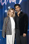 To gæster står foran blå Olivia-premierevæg og smiler til kameraet.