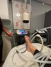 Fod på briks forbundet til medicinsk maskine med slanger i klinikrum.