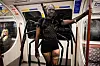 Kvindelig passager i edderkoppekostume står i en vogn på London Underground.