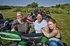 Medlemmer af Nordkap Veteran Knallertklub står ved klassiske knallerter på en grøn mark.