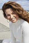 Julia Lahme i hvidt tøj sidder udendørs ved en kyststrækning.