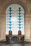 To historiske mineralvandsfontæner foran stor blå-hvid mosaikvæg i Wandelhalle.