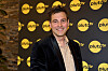 Person smilende foran sort væg med gule Pluto TV-logoer ved SMIL-kampen 2026.
