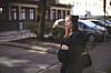 Gravid kvinde holder om maven, mens hun står på et fortov i en stille bygade