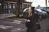 Gravid kvinde holder om maven, mens hun står på et fortov i en stille bygade