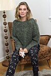 Kvinde i grøn strik sidder i brun lænestol og holder en hvid papirstjerne.