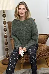 Kvinde i grøn strik sidder i brun lænestol og holder en hvid papirstjerne.