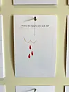 Plakat med enkel tegning af røde dråber hænger på væggen mellem andre ark.