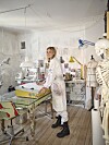 Nikoline Liv Andersen står ved arbejdsbord i lyst atelier fyldt med skitser og syudstyr.